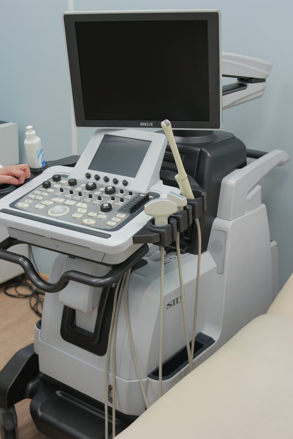 Modern ultrasound machine with a person's hand on the control panel.